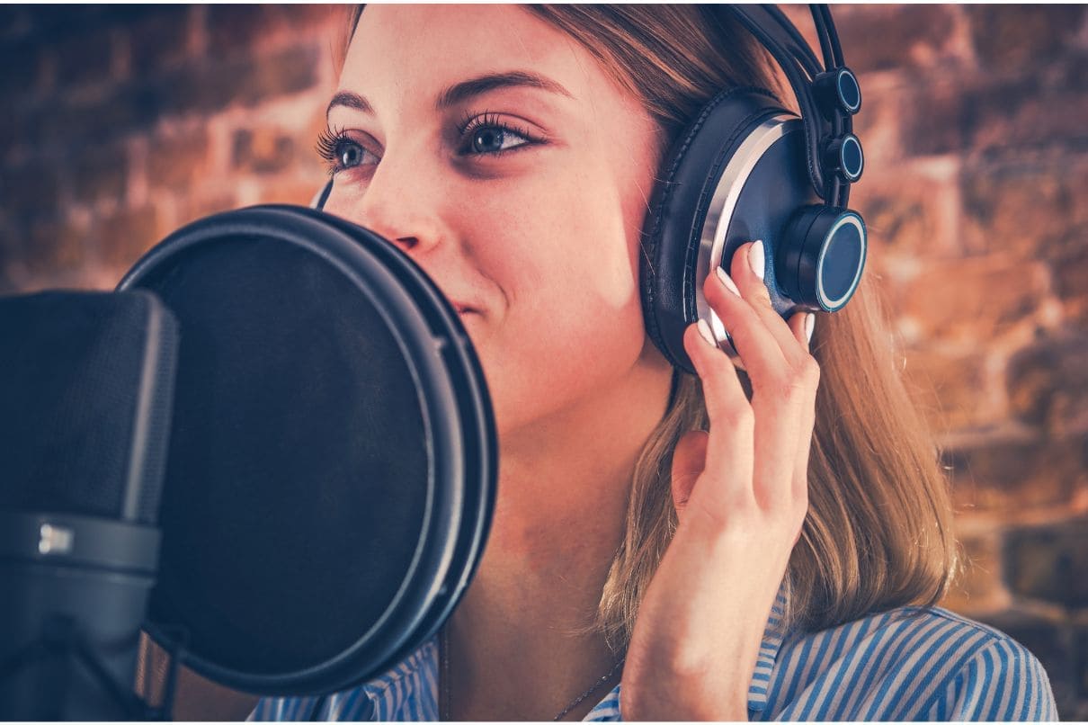 A woman recording music in a studio, surrounded by musical instruments and equipment.